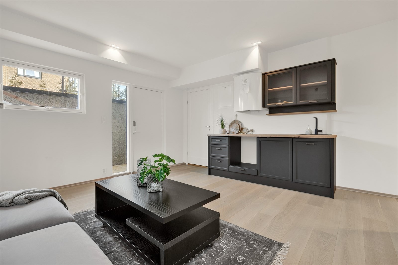 Kjøkkeninnredning med profilerte fronter og laminat og avsatt plass til hvitevarer. Inngang til baderom/vaskerom. Galleribilde