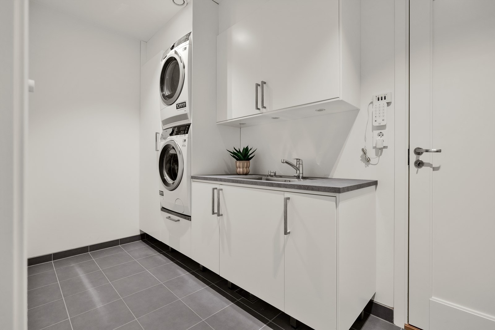 Romslig vaskerom med innredning med nedfelt kum og opplegg/plass for vaskemaskin/tørketrommel. Balansert ventilasjon. Inngang til garasjen på ca. 35 kvm med 2 elbilladere. Inngang også til teknisk rom. Galleribilde