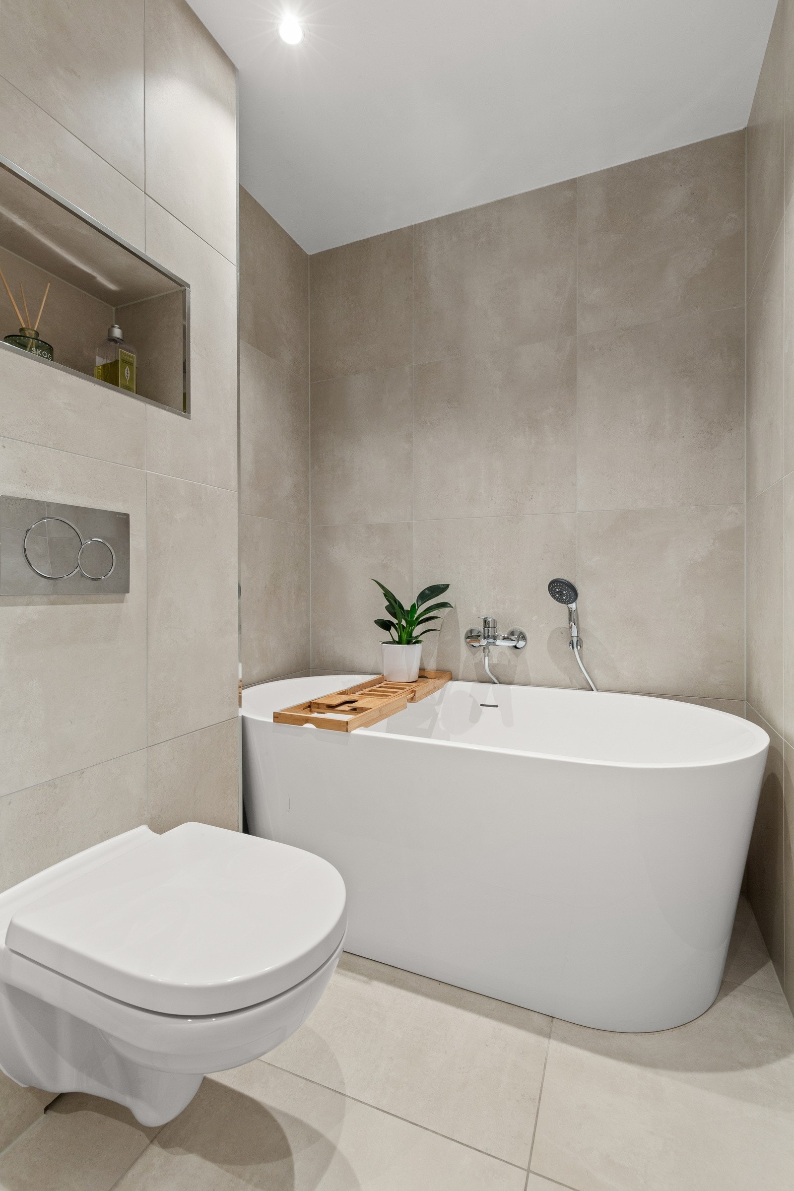 Rommet inneholder servantinnredning med helstøpt servant, speilskap med lys, vegghengt toalett, badekar og dusjhjørne. Galleribilde