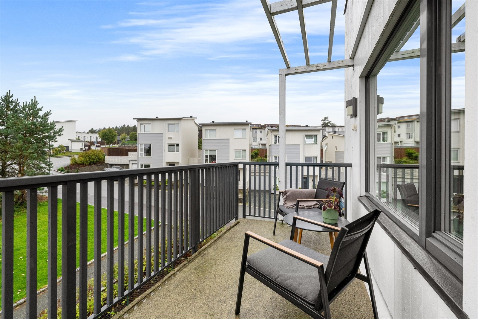 Balkongen har betonggulv, spilerekkverk av sortlakkert metall og pergola. På veggen er det montert utelys og stikk for ekstra funksjonalitet. Galleribilde