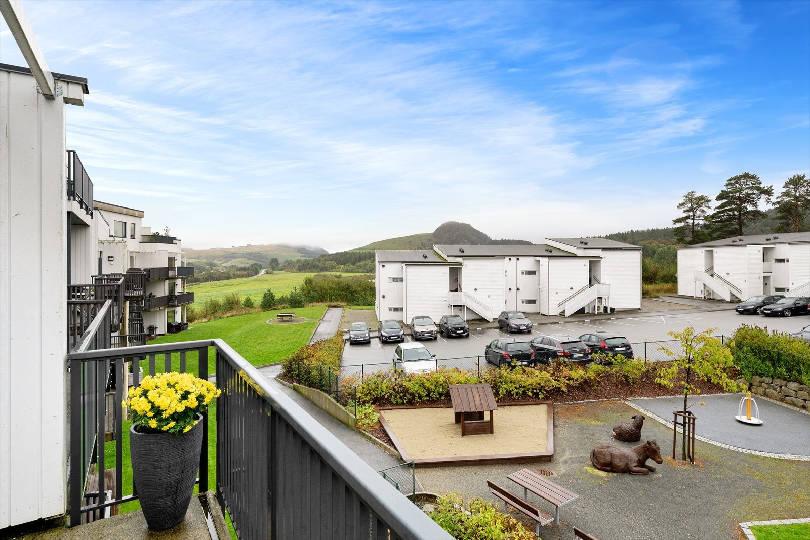 Fra balkongen kan man se rett ned på en forseggjort lekeplass og videre utover mot grønne sletter. Galleribilde