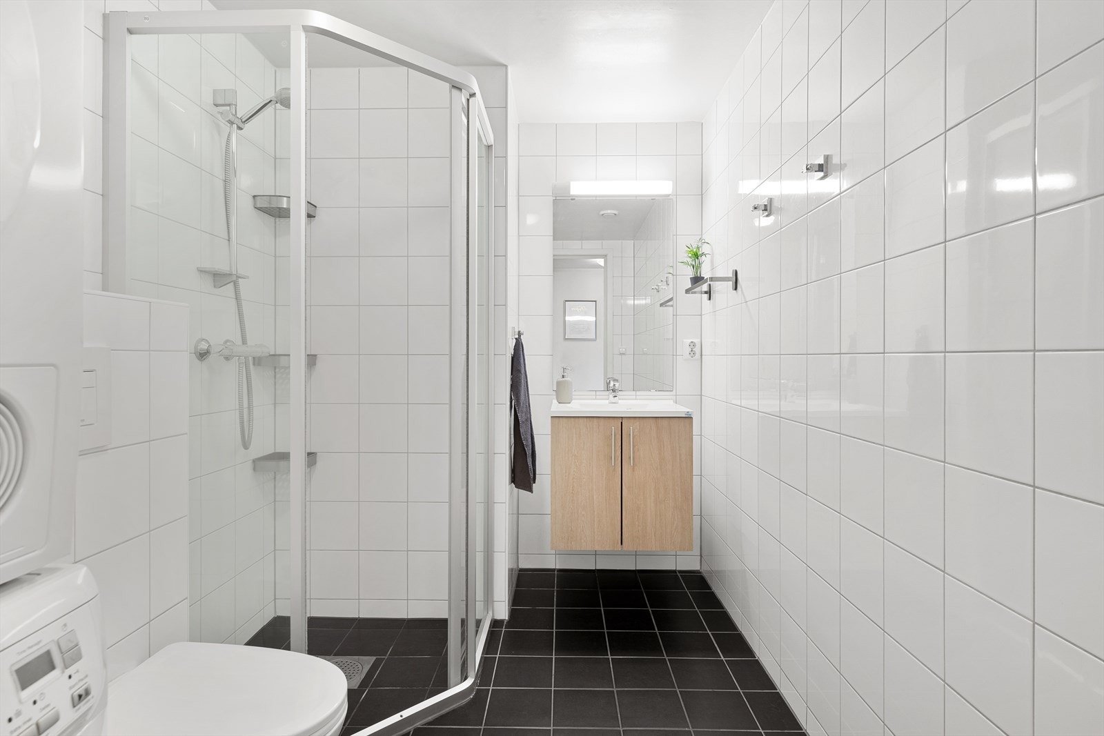 Baderomsinnredningen har like fronter som på kjøkkenet og består av et benkeskap med heldekkende servant. Over servanten er det et høyt speil med belysning. Galleribilde