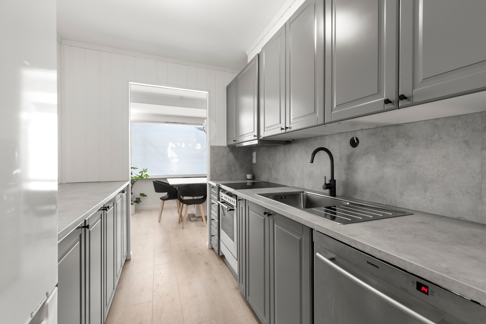 Kjøkkeninnredning med profilerte fronter. Benkeplate av laminat. Nedfelt oppvaskkum av rustfritt stål med ett-greps armatur. Galleribilde