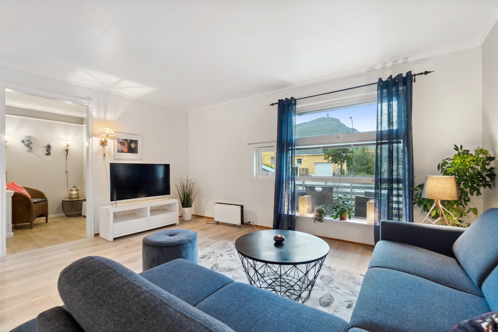 Lys og velholdt stue med store vindu som gir rikelig med naturlig lys. Galleribilde