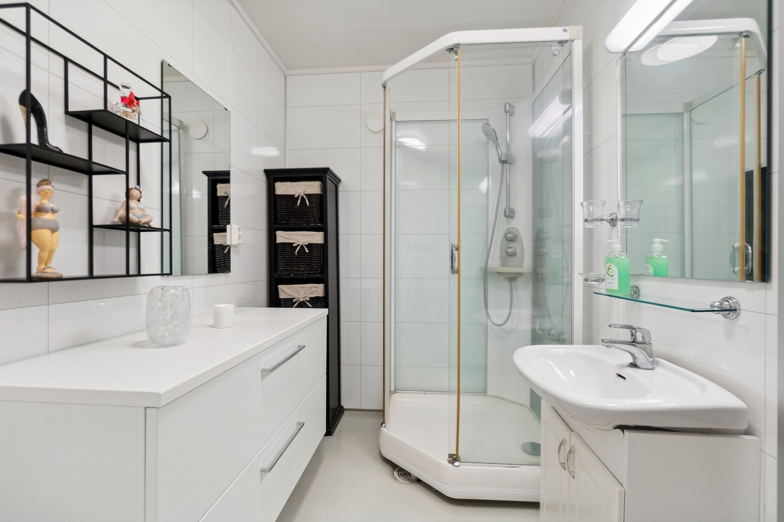 Bad med lyse baderomsplater og vinylbelegg. Badet er installert med et større dusjkabinett. Galleribilde