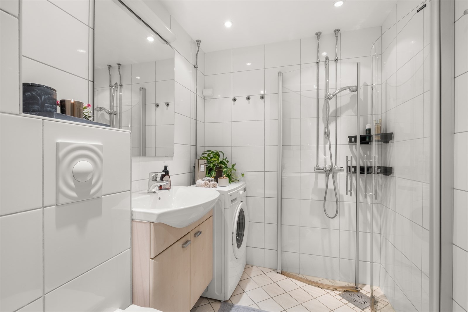 Badet inneholder dushjørne med innfellbare dusjdører, servant med oppbevaring, toalett og opplegg for vaskemaskin. Vaskemaskin kan medfølge om ønskelig Galleribilde