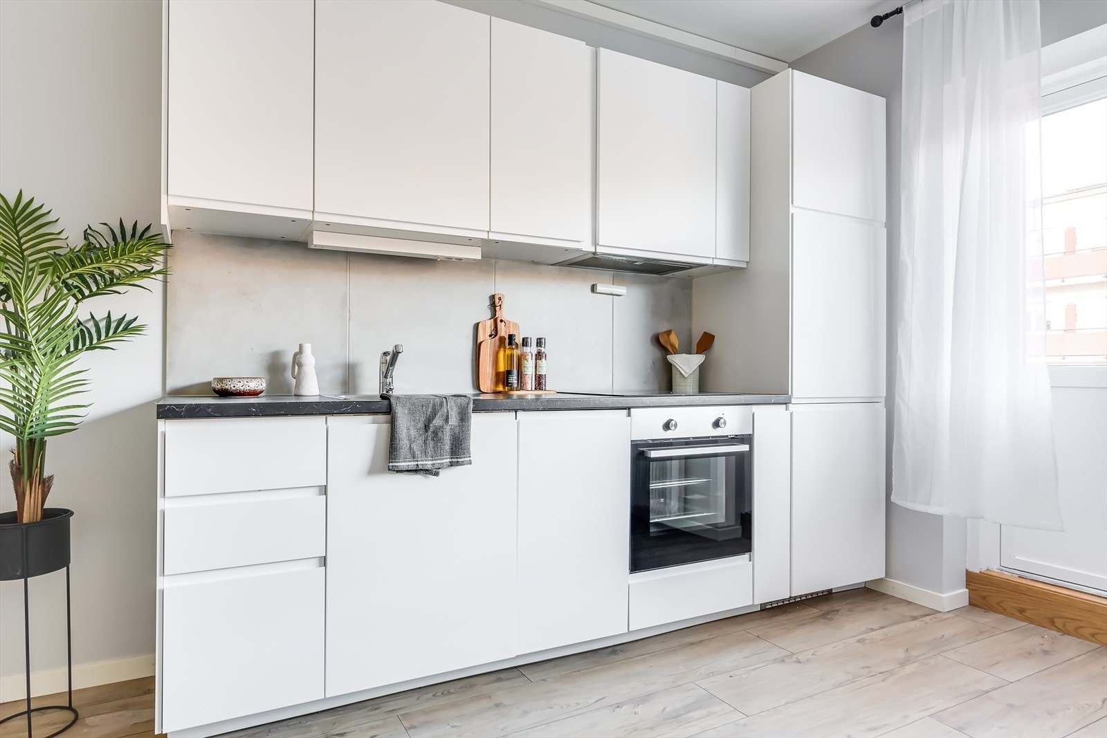 Stilren kjøkkeninnredning med hvite, glatte fronter og benkeplate av laminat Galleribilde