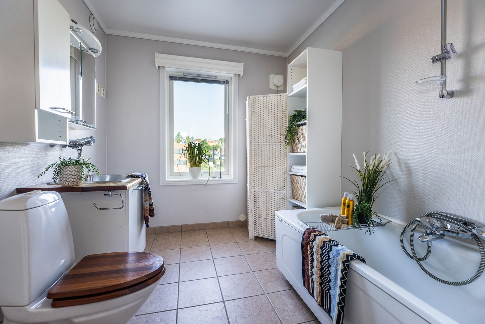 Lyst og romslig bad innredet med servantinnredning med utslagsvask, speilskap, badekar og toalett. Det er opplegg for vaskemaskin i rommet. Galleribilde