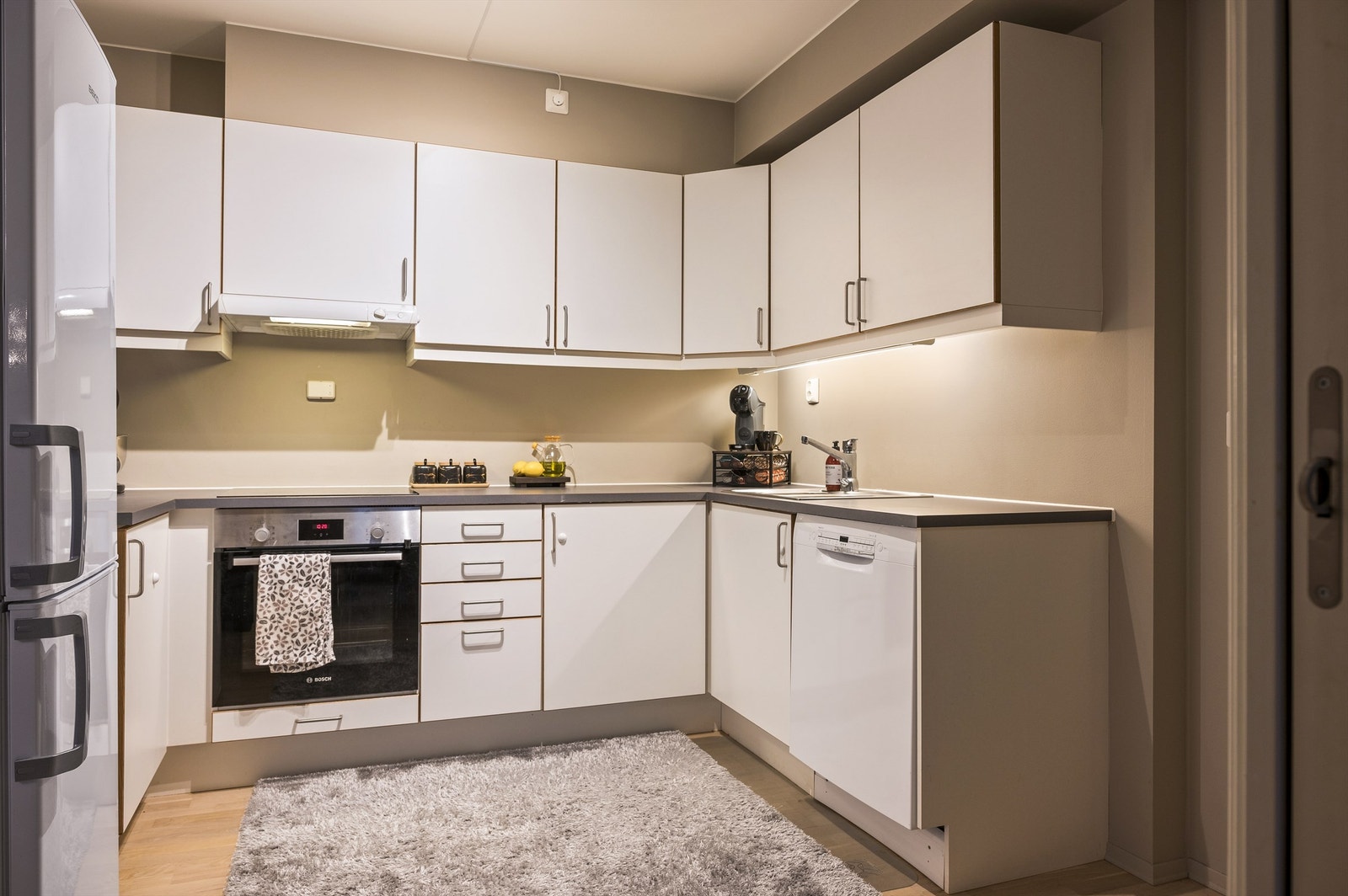 Stekeovn og oppvaskmaskin fra 2022. Belysning, stikkontakter og kjøkkenvakt er montert mellom benk og overskap. Galleribilde