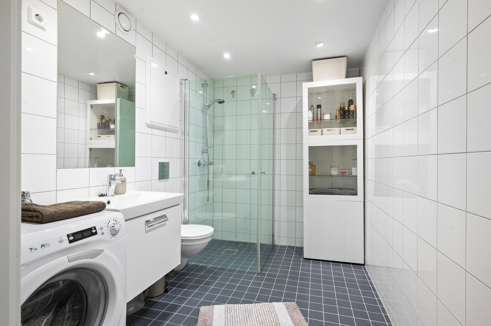 Innbydende og meget romslig bad med flislagte vegg- og gulvflater og varme i gulv samt downlights i himling Galleribilde