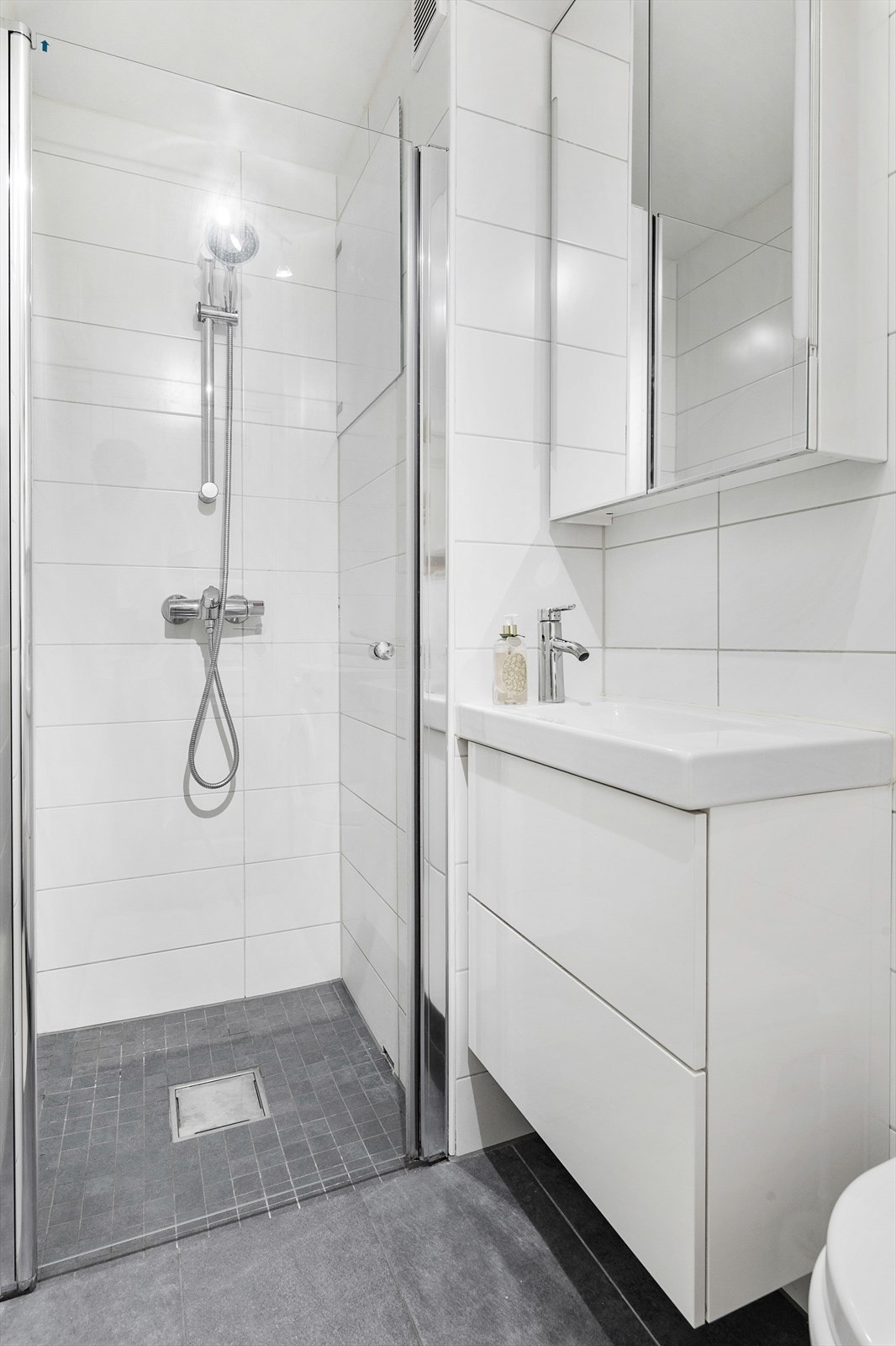 Delikat bad med opplegg for vaskemaskin og god oppbevaringsplass i speilskap og skuffer under servant. Galleribilde