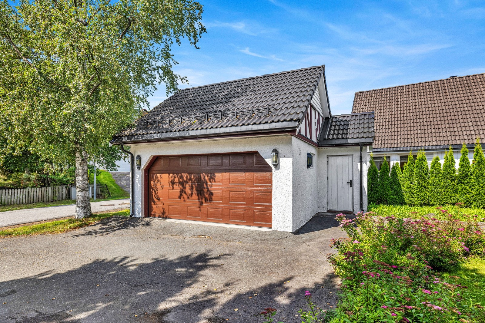 Det tilhører en romslig garasje med elektrisk port, og det er også plass til biler på gårdsplassen. Det er montert lader for elbil i garasjen. Det er også mye lagringsplass på garasjeloft. Galleribilde
