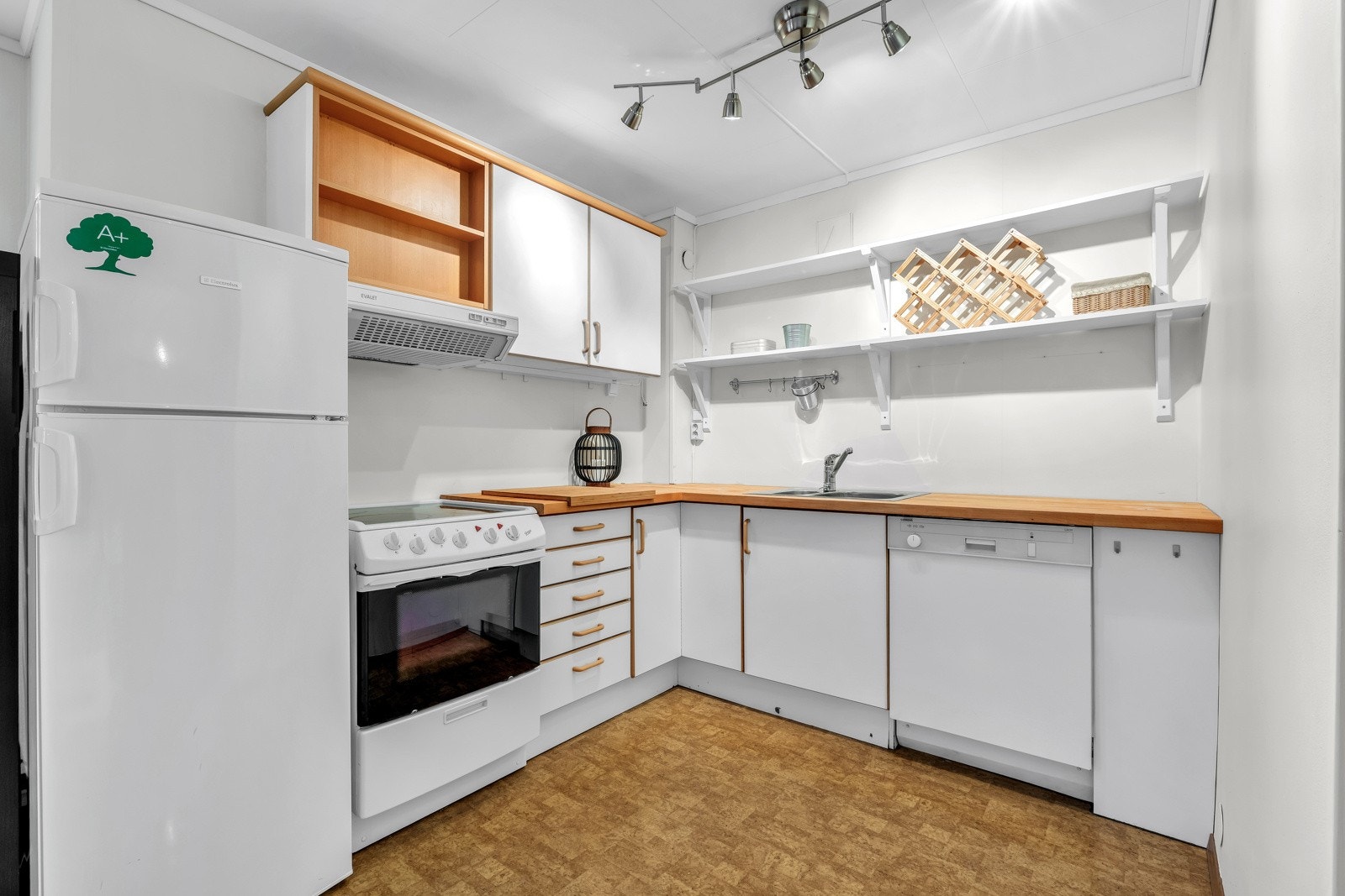 Kjøkkeninnredningen i underetasjen har hvite, glatte fronter, hyller og en heltre benkeplate med nedfelt oppvaskkum. Galleribilde