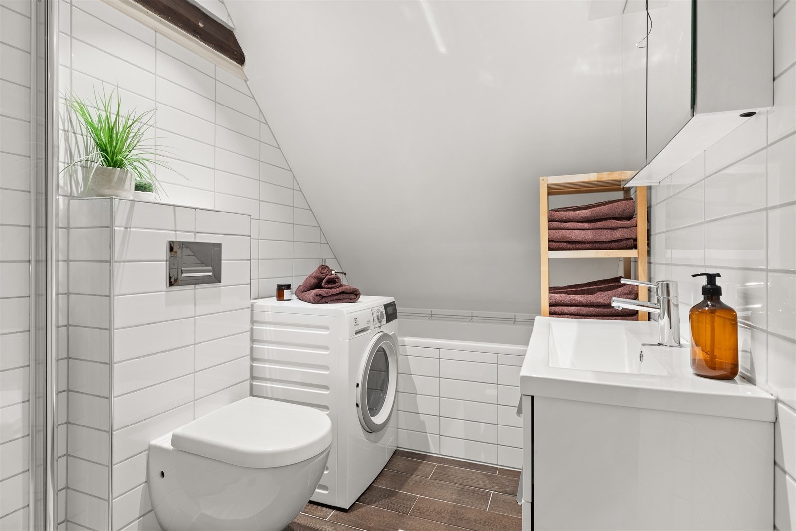 Badet er lekkert og fremstår med hvite veggfliser og mørke gulvfliser med underliggende gulvvarme. Galleribilde