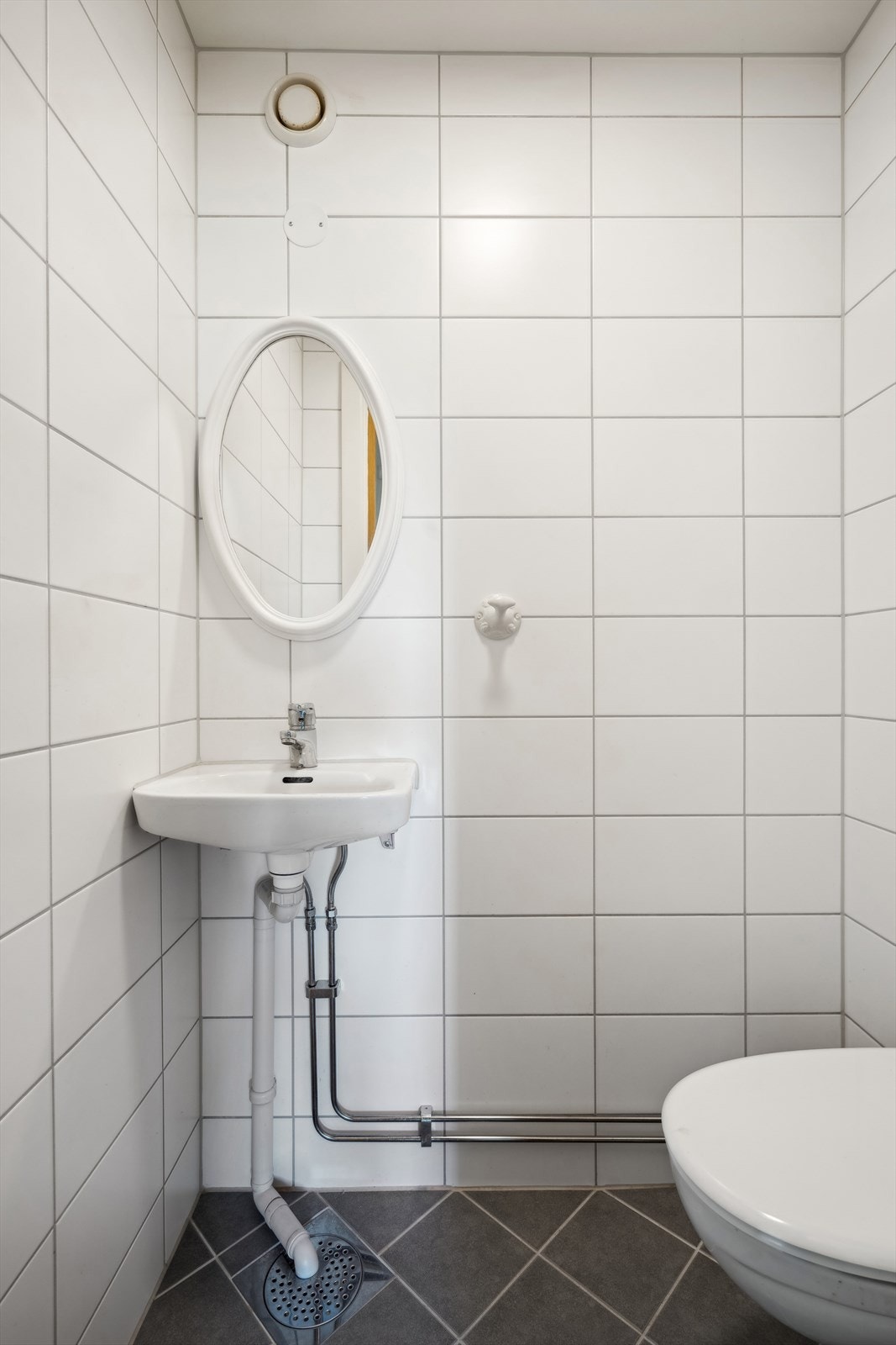 WC| Oppgradert i 2019 og har flislagt gulv og vegger, med himling bestående av malte plater. Utstyrt med vegghengte toalett, porselenservant med ettgreps armatur, speil og taklampe som gir god belysning. Galleribilde