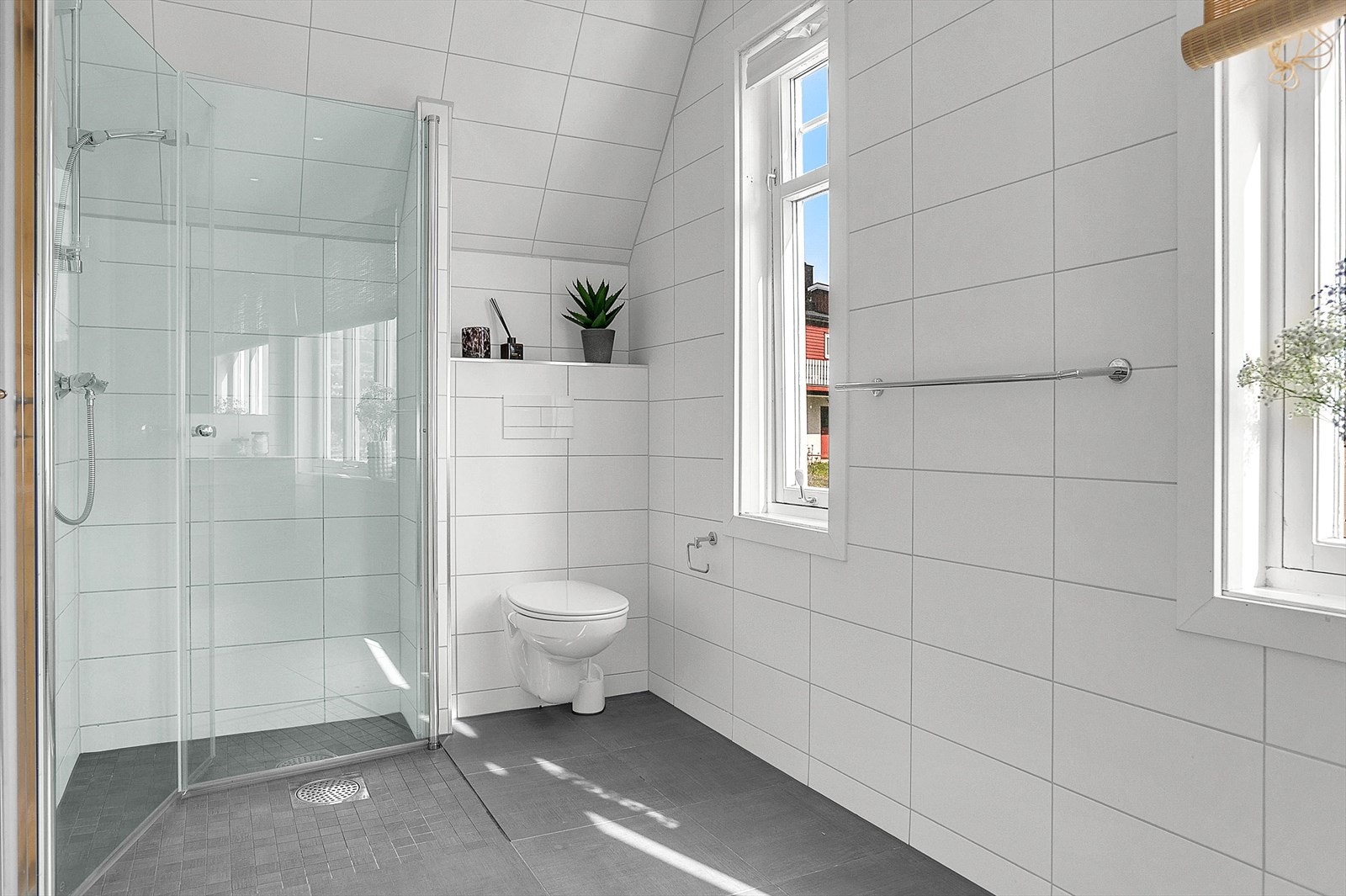 Pent flislagt og utstyrt med dusjhjørne, vegghengt toalett, varme i gulv, downlights i himling og baderomsinnredning med heldekkende servant. Galleribilde