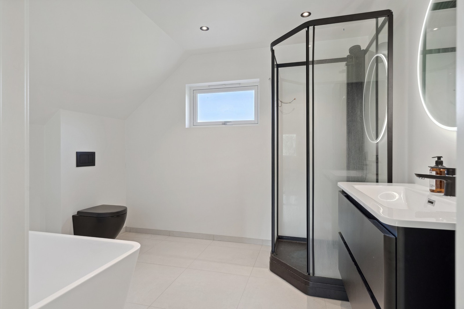 Bad med dusjkabinett, downlights i tak, badekar og servant med innredning. Galleribilde