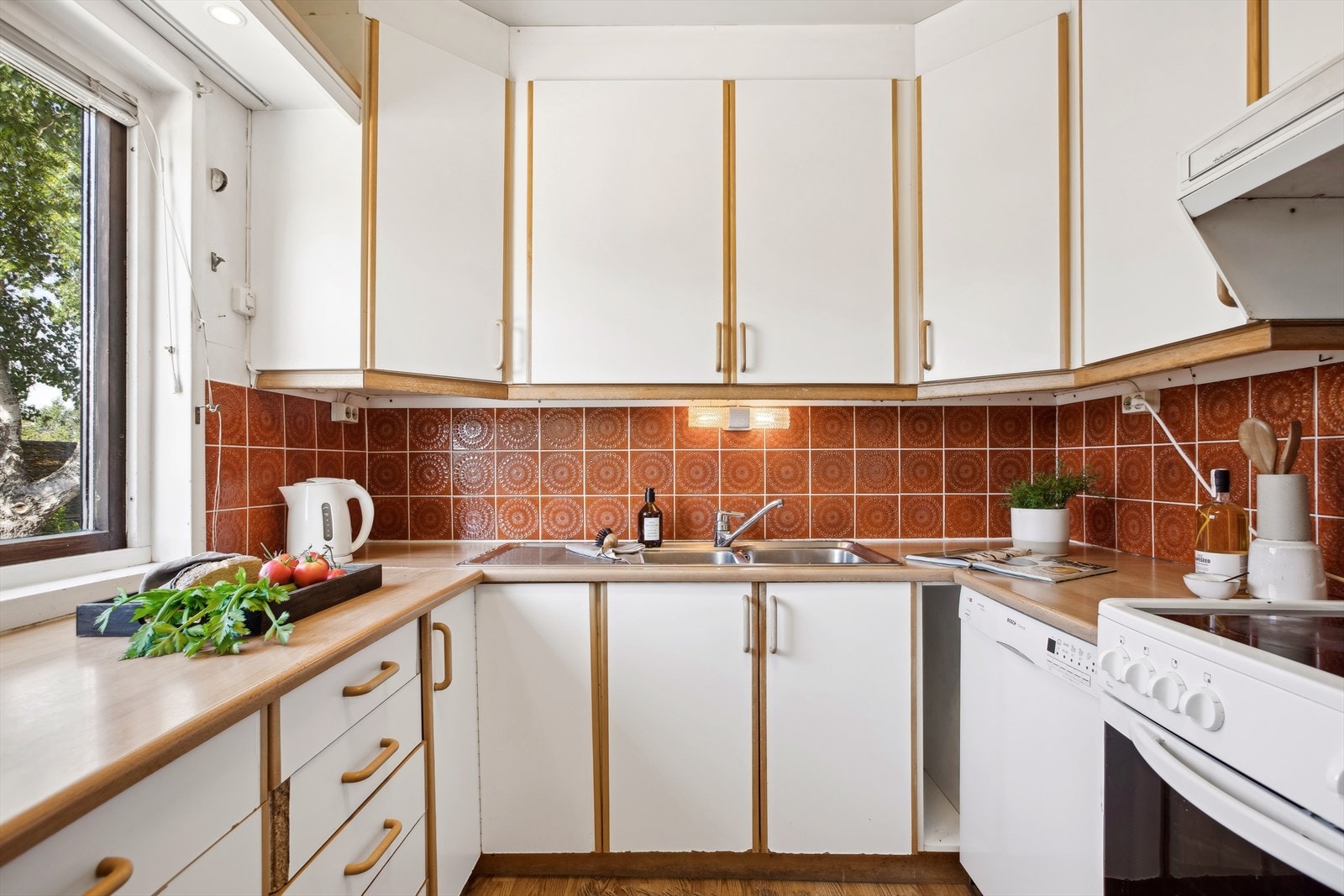 Kjøkkeninnredningen er av eldre dato, og er utført med hvite, glatte fronter og benkeplate med kum. Galleribilde