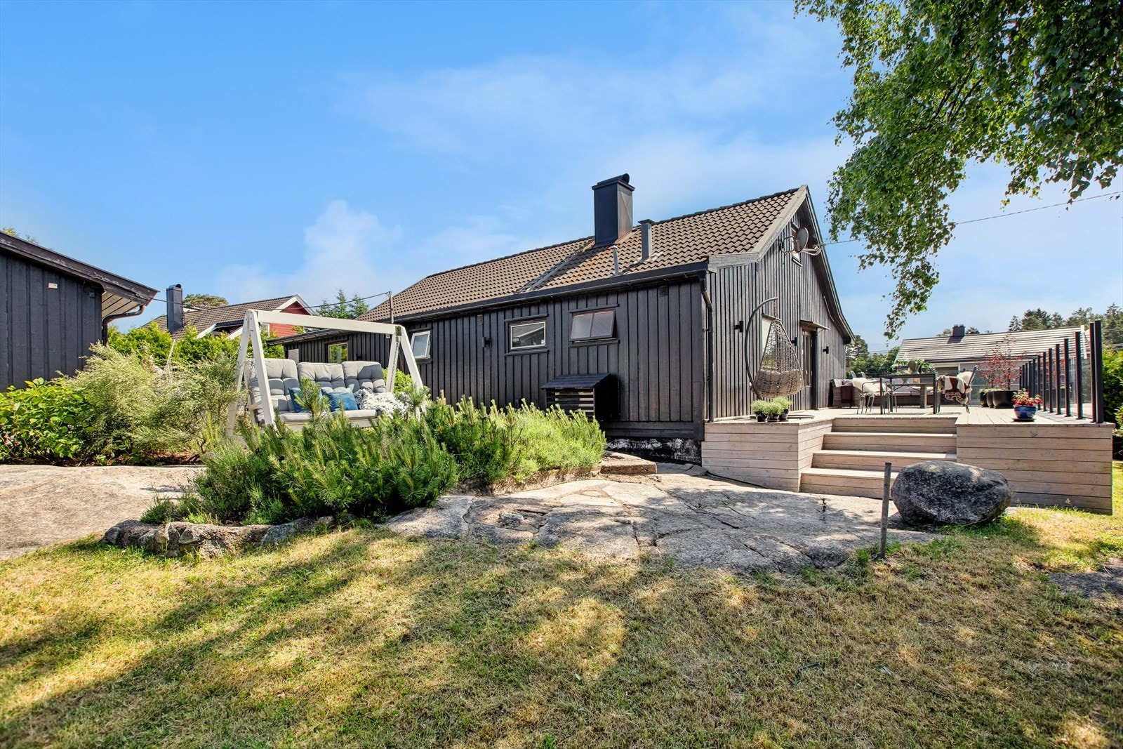 Eiendommen byr på en stor terrasse og en frodig og solrik hage. Galleribilde