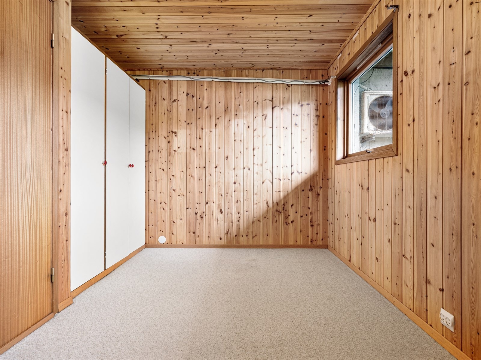 Soverom med teppe på gulv og panel på vegger. Gardreobeskap. Galleribilde