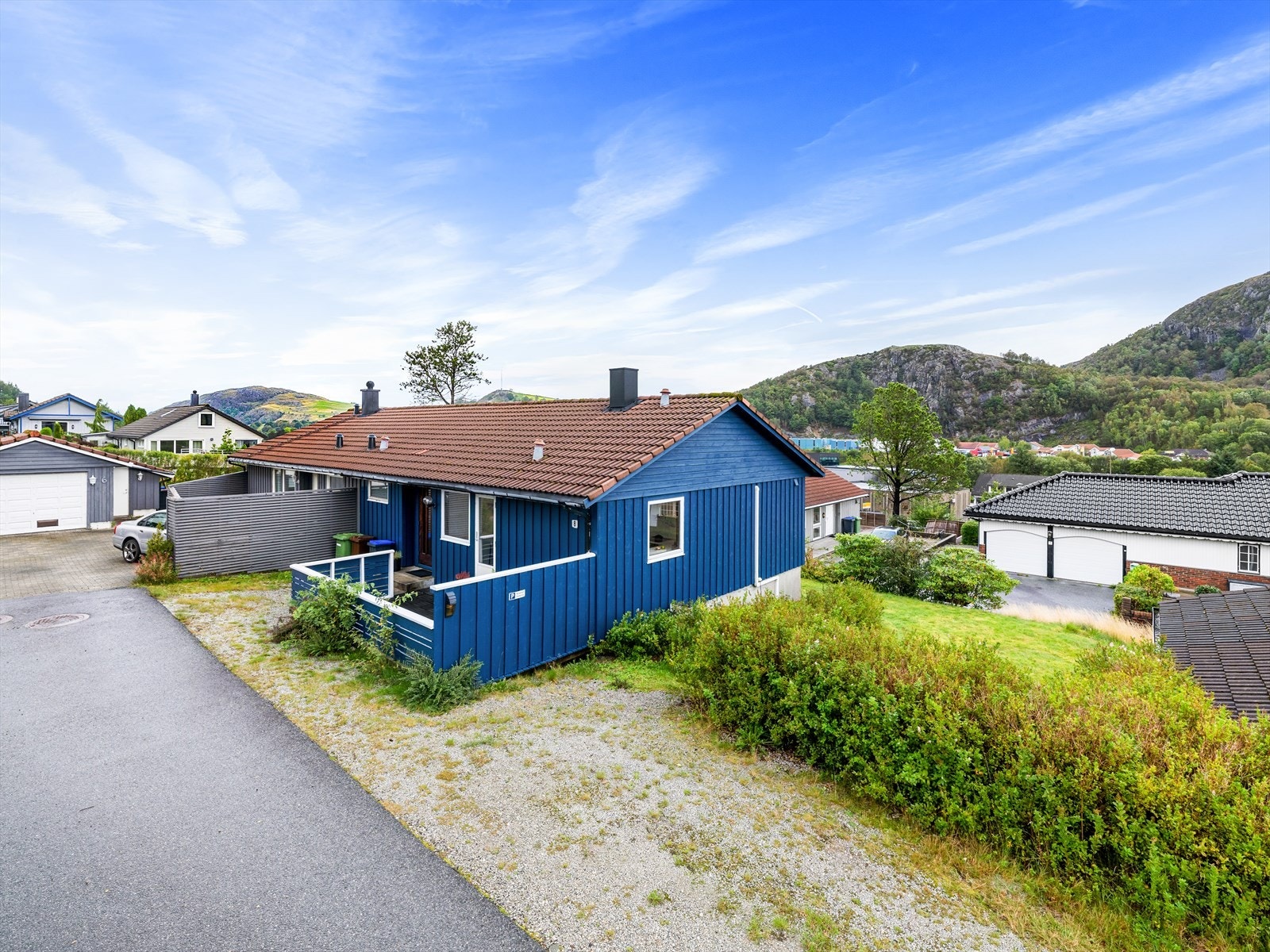 Tomt opparbeidet med grus/p-plass og terrasse ved inngangsparti. Plen i front av bolig. Galleribilde