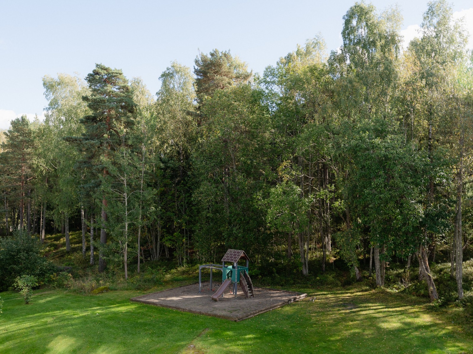 Balkongen vender ut mot grønne fellesarealer med lekeplass, som ligger helt inntil skog og mark. Galleribilde