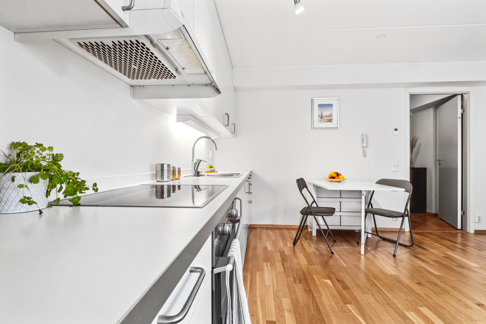 Langstrakt kjøkkeninnredning vendt mot stuen. Spisegruppen finner sin naturlige plass i direkte tilknytning. Galleribilde