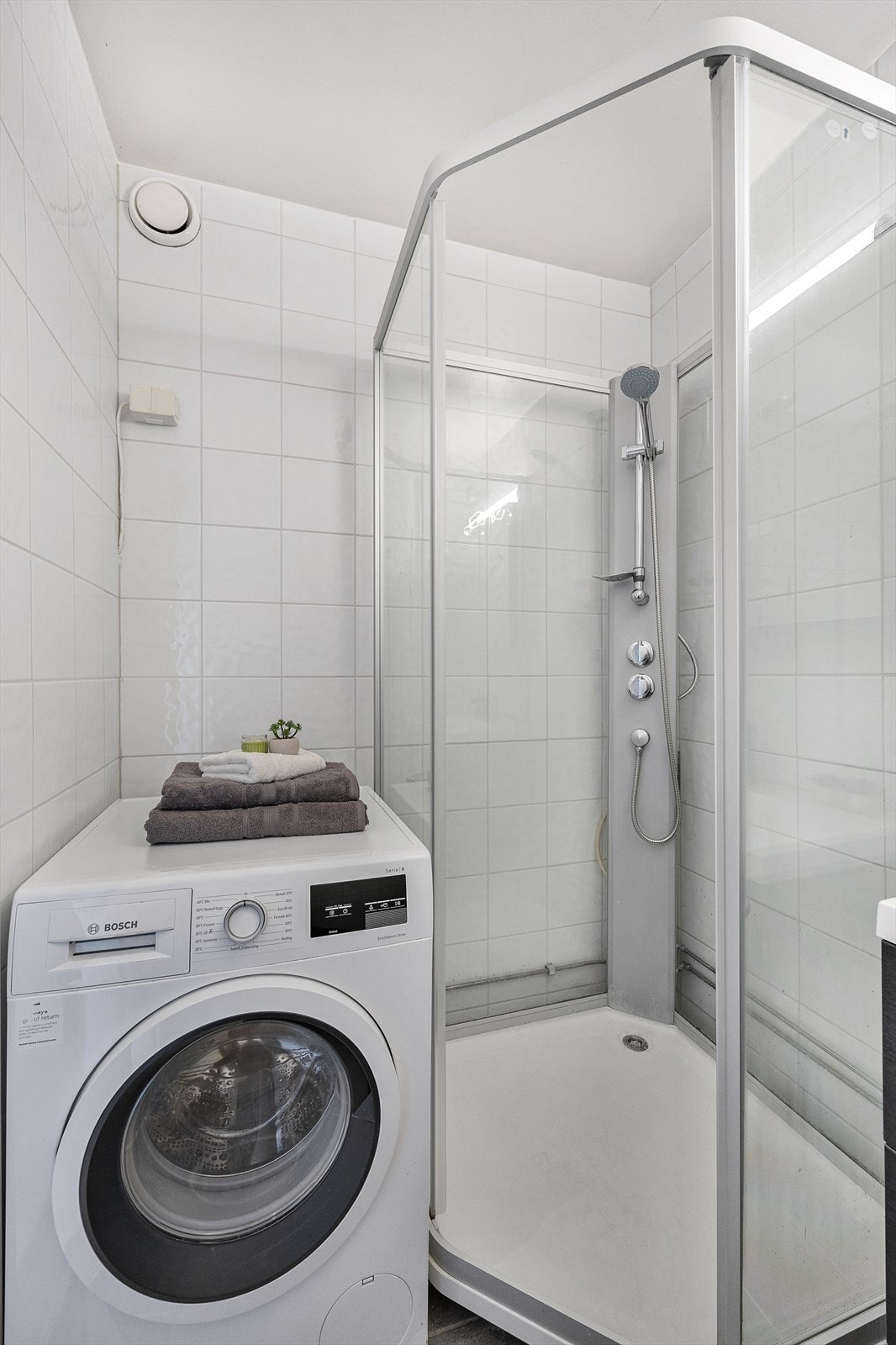 Badet er utstyrt med dusjkabinett, vask og opplegg for vaskemaskin Galleribilde