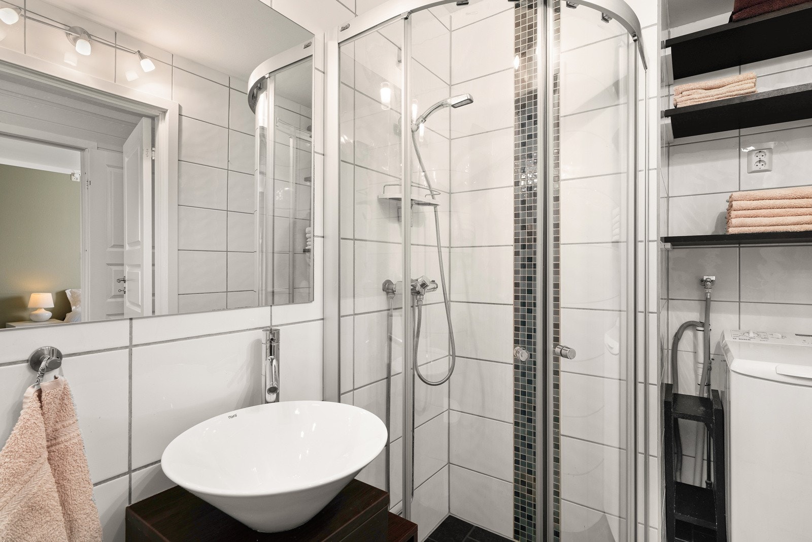 Badet er videre utstyrt med overliggende servantskål, wc, dusjhjørne, opplegg for vaskemaskin og gulvvarme. Galleribilde