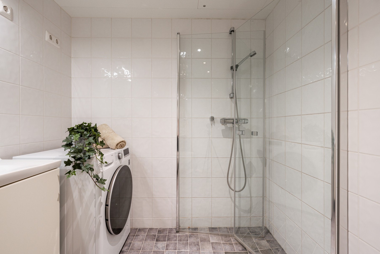 Badet er utstyrt med vegghengt toalett, dusjhjørne, servantskap og opplegg for vaskemaskin. Galleribilde