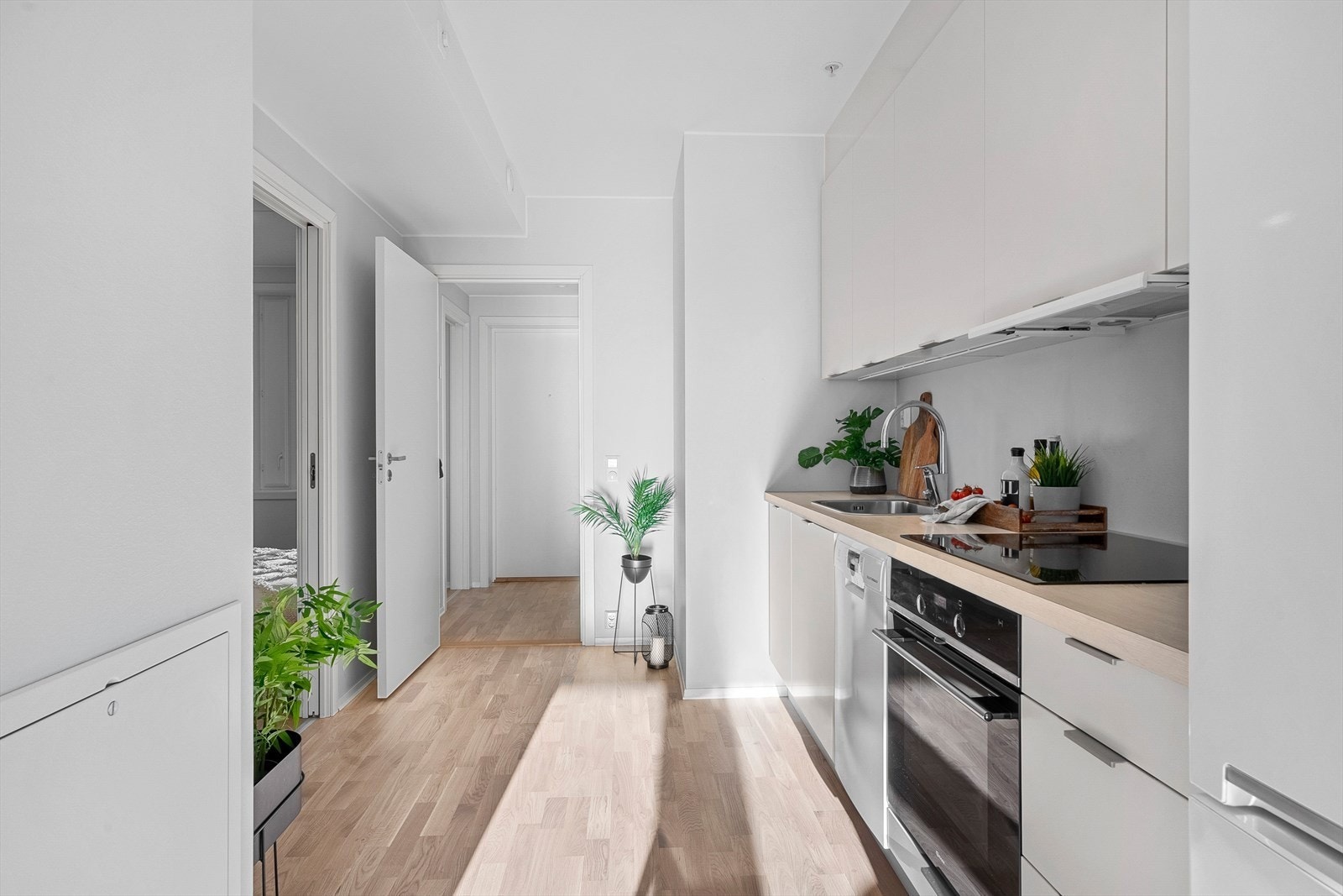 Stilfult og moderne kjøkken fra byggeår med glassplater på vegg over benkeskap og laminat benkeplate med nedfelt kum i rustfritt stål. Galleribilde