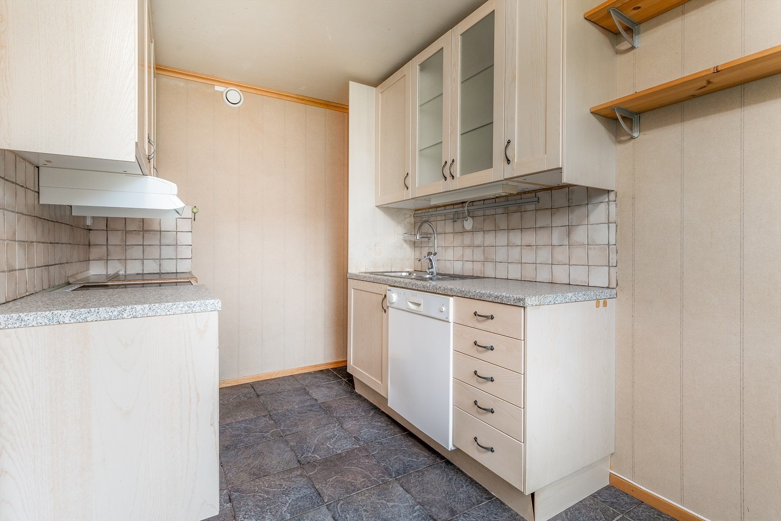 Kjøkkenet har en profilert innredning med noe glasskap, laminat benkeplate og flis over kjøkkenbenk. Det er ventilator med avtrekk ut og opplegg for oppvaskmaskin. Galleribilde