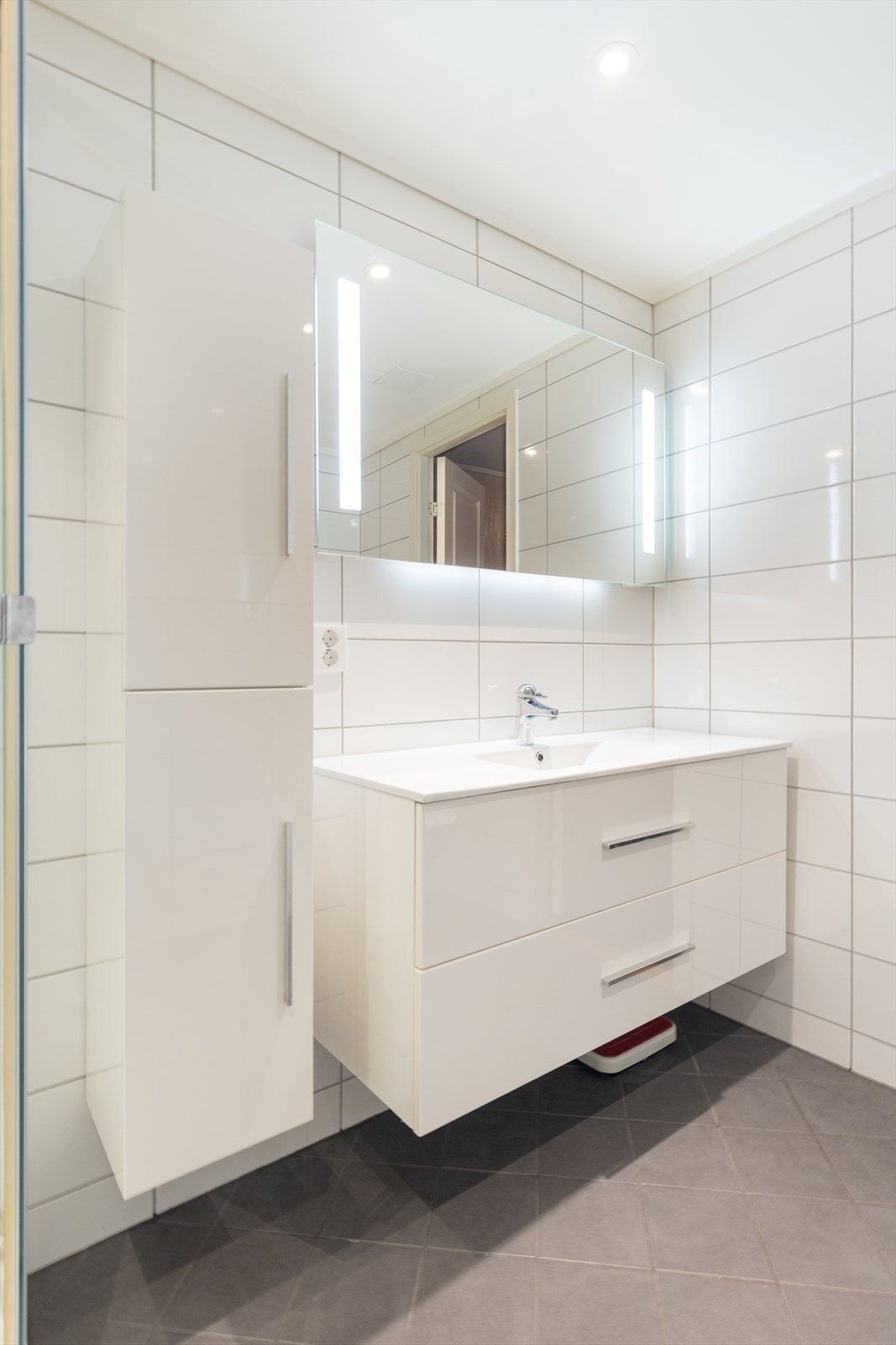 Innredningen har heldekkende hvit vask, dype underskuffer med slette fronter og speil med lys. Innredningen har også et høyskap med ekstra oppbevaringsplass. Galleribilde