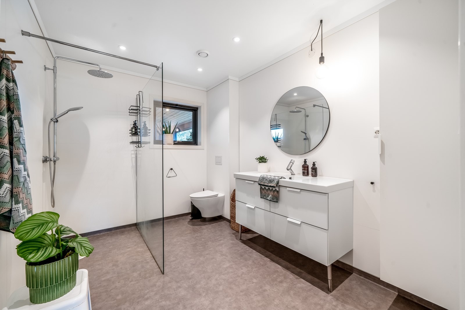 Bad med baderomsplater og belegg på gulv. Badet er innredet med baderomsinnredning. toalegg og dusjløsning med glassvegg. Galleribilde