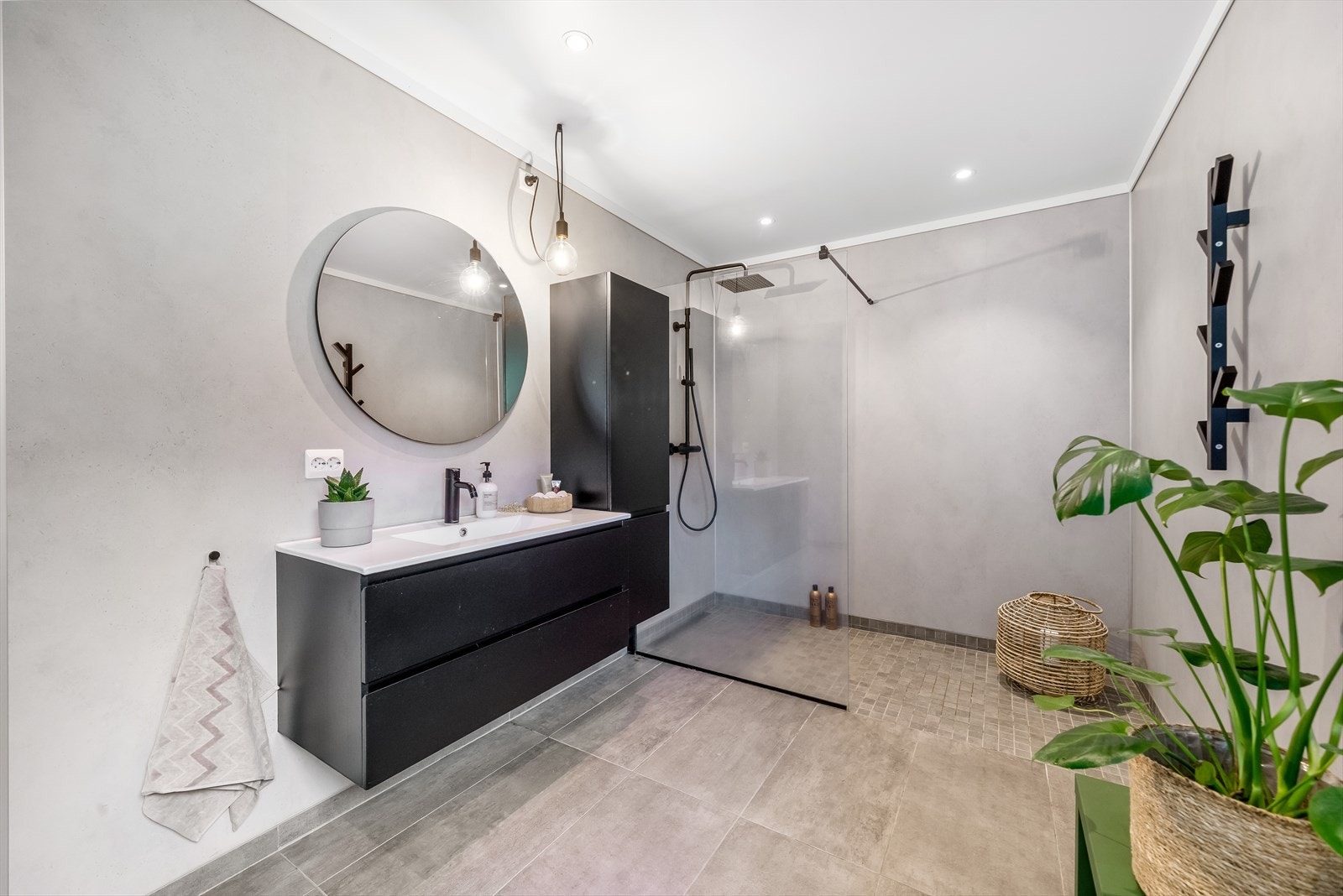 Moderne innredet bad med fliser på gulv og baderomsplater på vegg. Innredet med baderomsinnredning, toalett og dusjløsning med glassvegg. Galleribilde