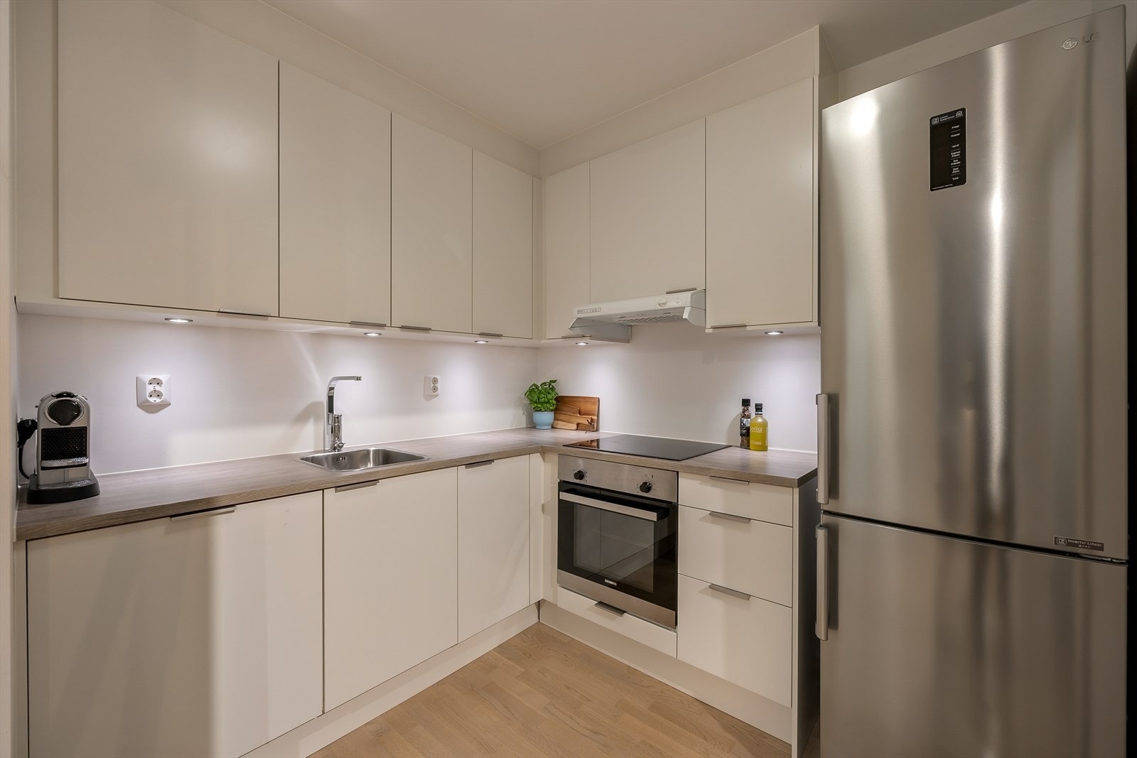 Et romslig og delikat kjøkken med integrerte hvitevarer som kjøl-/fryseskap, stekeovn, platetopp, kjøkkenvifte med utkast ut og oppvaskmaskin. Galleribilde