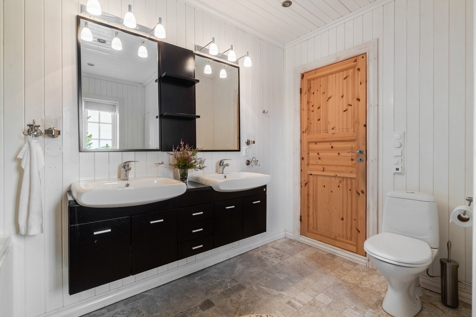 Hytta har et romslig familiebad hvor det er flislagt gulv med varmekabler. Her er det innredning med dobbel servant samt speil på vegg med hyller og overlys. Galleribilde