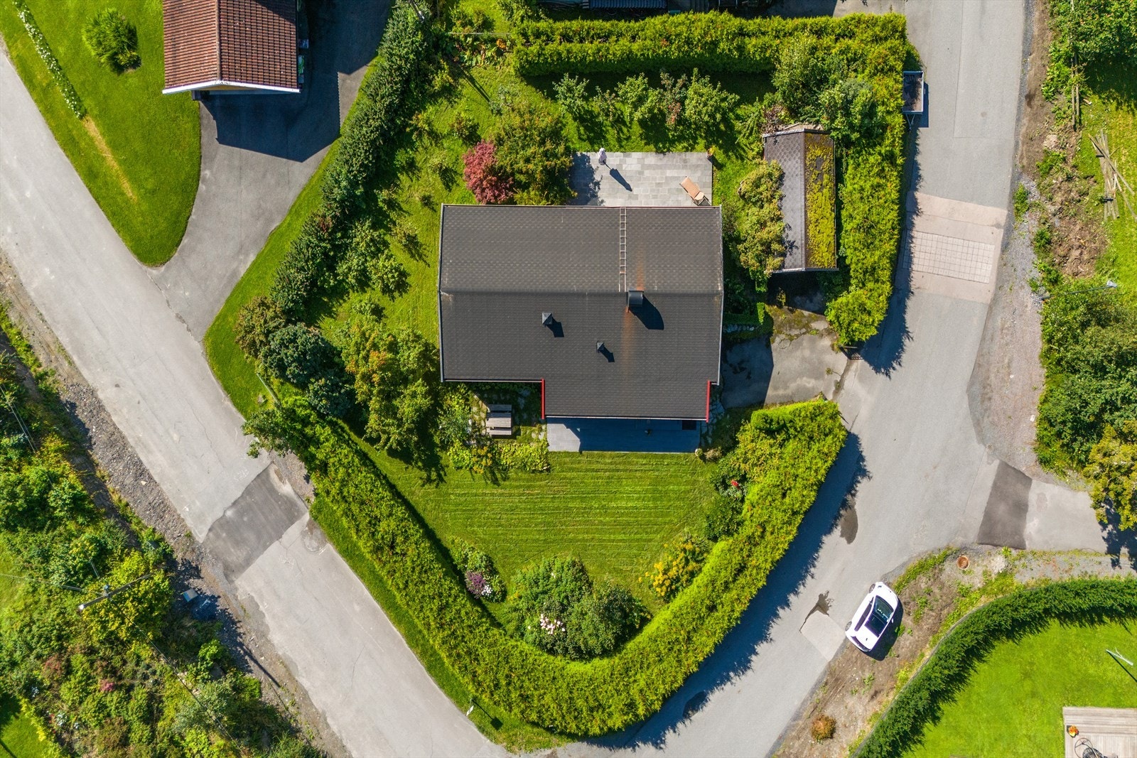 Tomten er tilnærmet flat og er pent opparbeidet med gressplen, stedlige vekster og tuja-hekker rundt store deler av tomten. Asfaltert gårdsplass foran garasjen. På terrassene/ i hagen er det gode solforhold og god plass til utemøbler, grill, blomster e.l Galleribilde