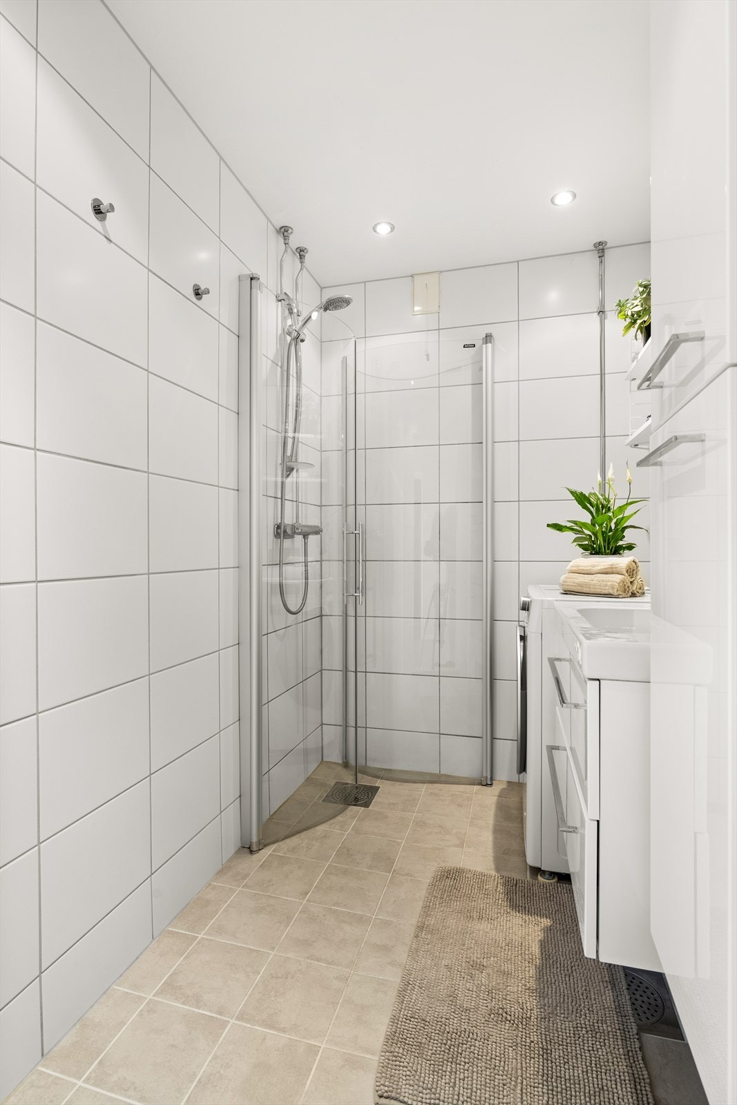 Badet har varme i gulv, opplegg for vaskemaskin, dusjhjørne og servant med oppbevaring Galleribilde