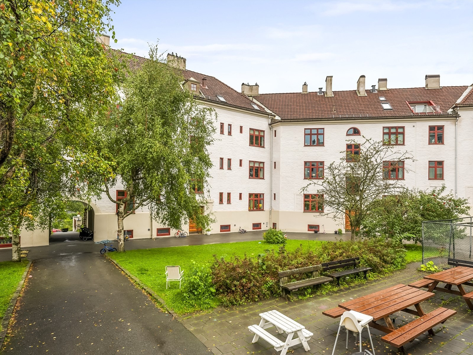 Grønn bakgård med sittegrupper og lekeplass for barn. Galleribilde
