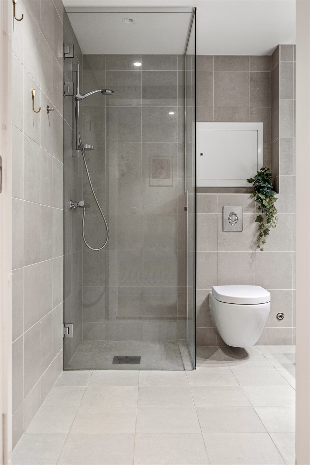 Badet er utstyrt med rørfordelingsskap, stoppekran, mekanisk avtrekk, innfellbare dusjdører, veggmontert toalett og servantskap med ettgreps blandebatteri fra Hansgrohe Galleribilde