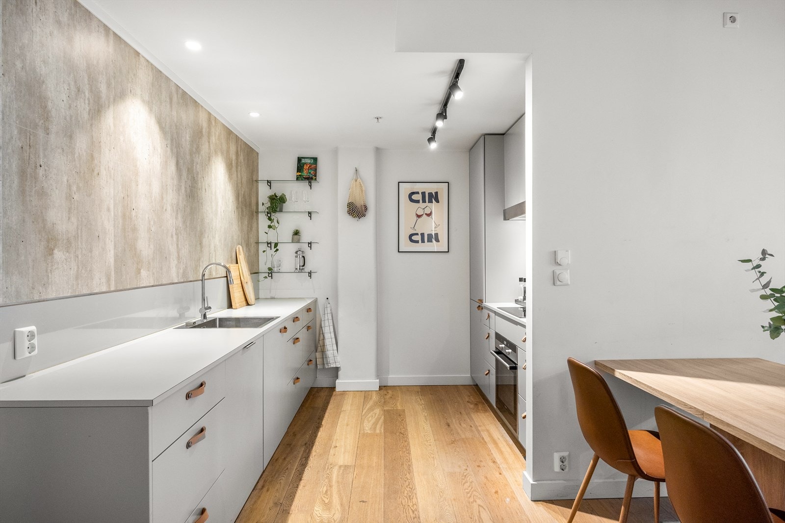 Kjøkkenet er praktisk plassert litt tilbaketrukket fra stuen, og har en stilren innredning med grå, glattlakkerte fronter og laminat benkeplate Galleribilde