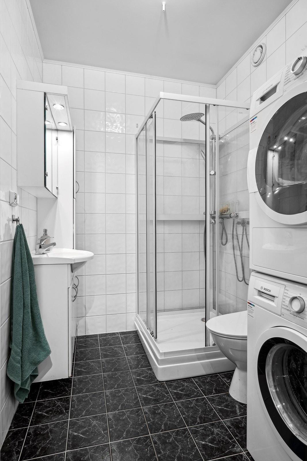 Badet er komplett flislagt og har varmekabler i gulv. Utstyrt med dusjkabinett og opplegg for vaskemaskin og tørketrommel Galleribilde