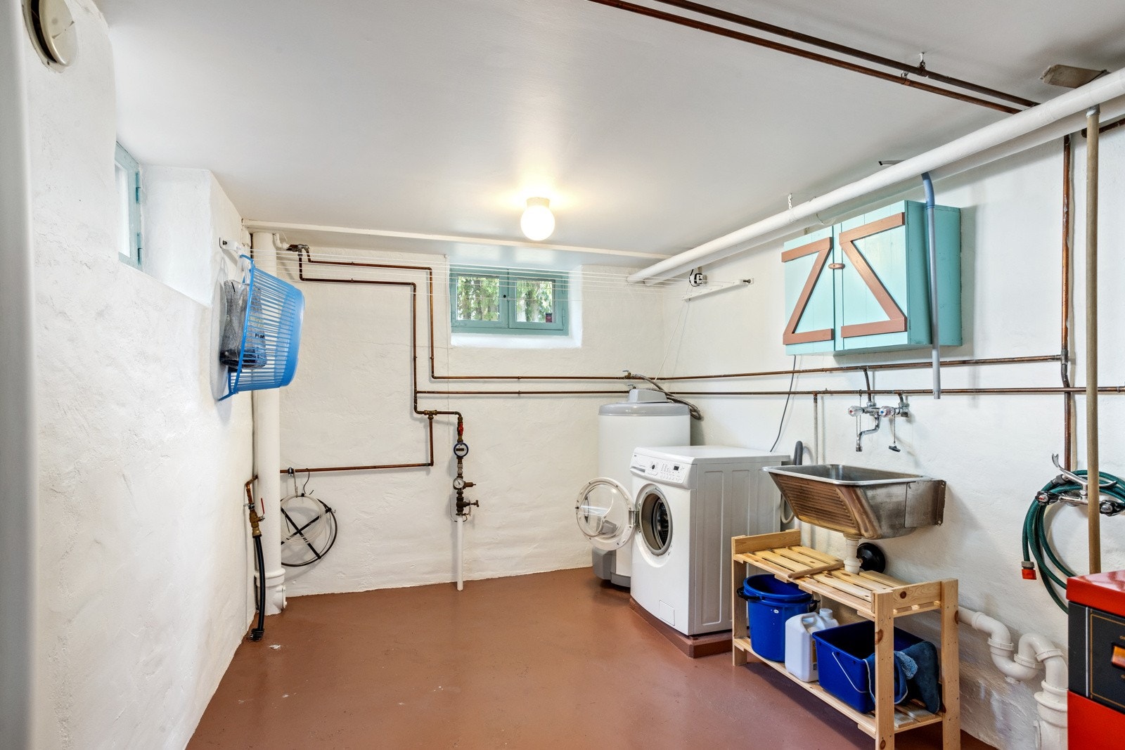 I kjelleren finner du et kombinert vaskerom og fyr-rom, komplett med vaskekum og opplegg for vaskemaskin Galleribilde