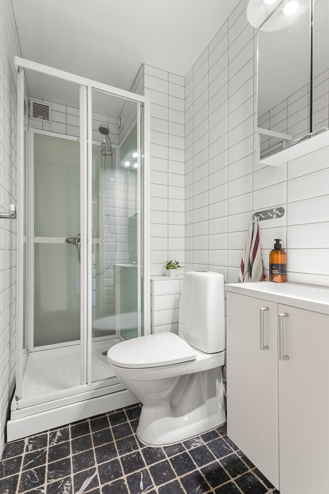 Separat toalettrom med dusjkabinett, toalett, speilskap og og servantinnredning. Oppgradert med nytt rør-i-rør system i 2020. Galleribilde