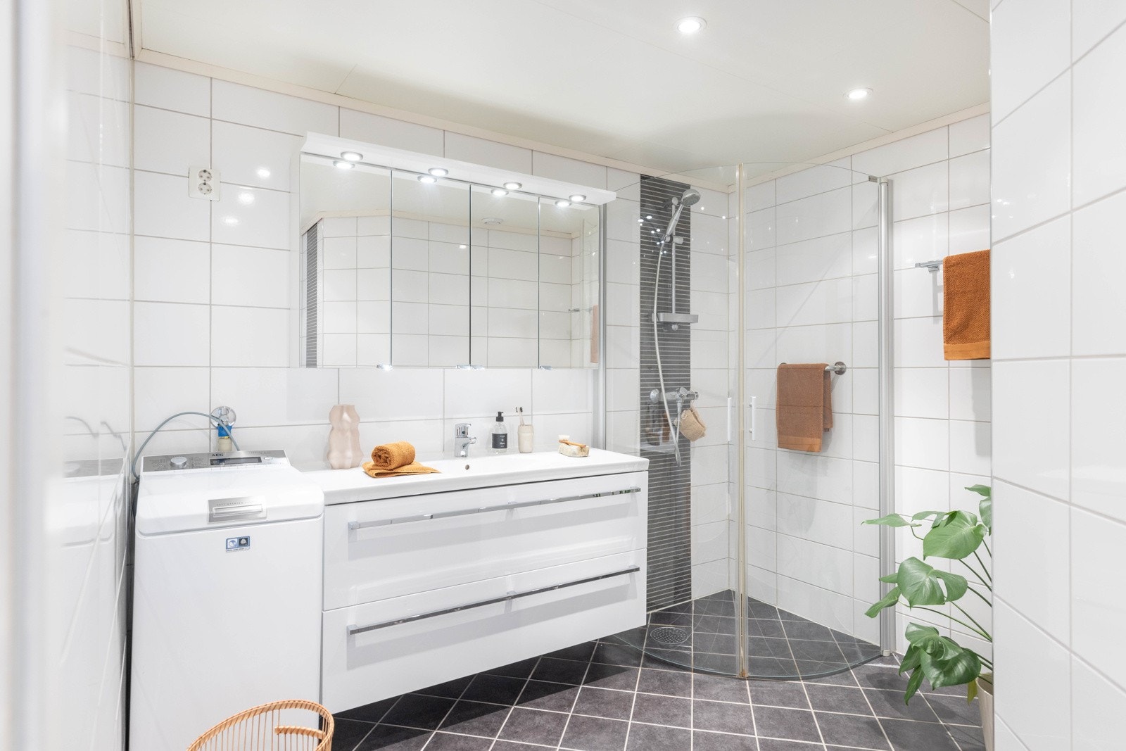 Badet er innredet med baderomsmøbel med høyglans fronter med speilskap med belysning over, dusj med foldevegger i herdet glass. Det er også opplegg for vaskemaskin (smal modell) og tørketrommel. Galleribilde