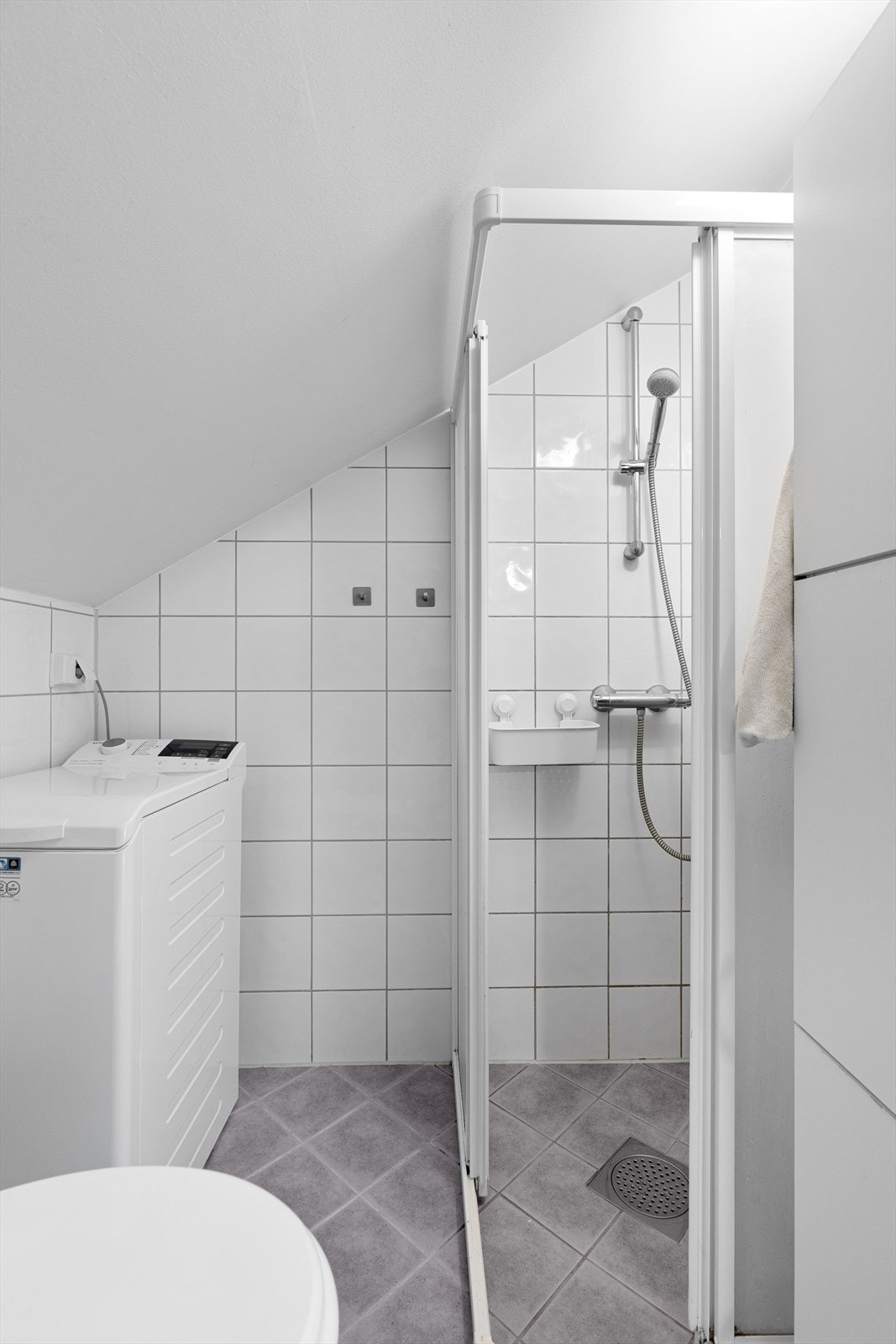 Dusjhjørne rett på gulv med sokkelprofil, skyvedører av glass, dusjbatteri og hånddusj. Videre er det både plass og opplegg for vaskemaskin. Galleribilde