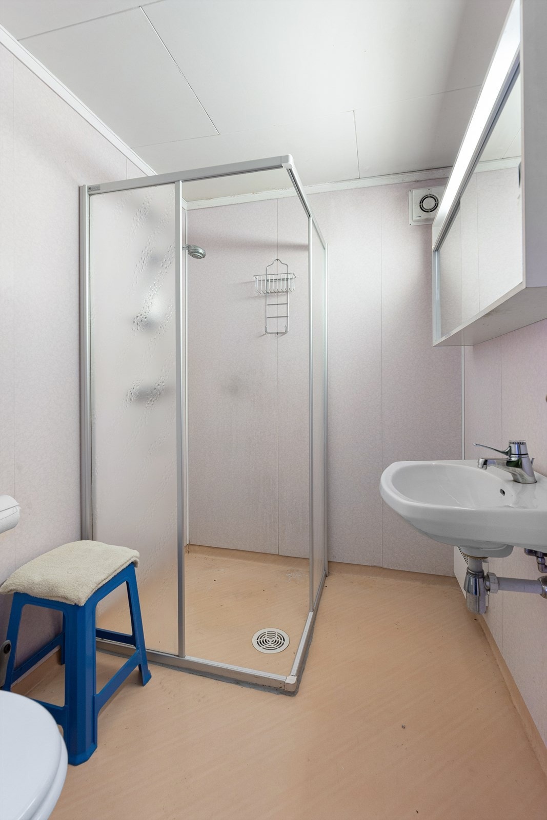 Badet i underetasjen er innredet med dusjplass som er avgrenset med skyvedørs-vegger, gulv-montert toalett og servant. Over servant er det vegghengt skap med skyvbare speildører. Galleribilde