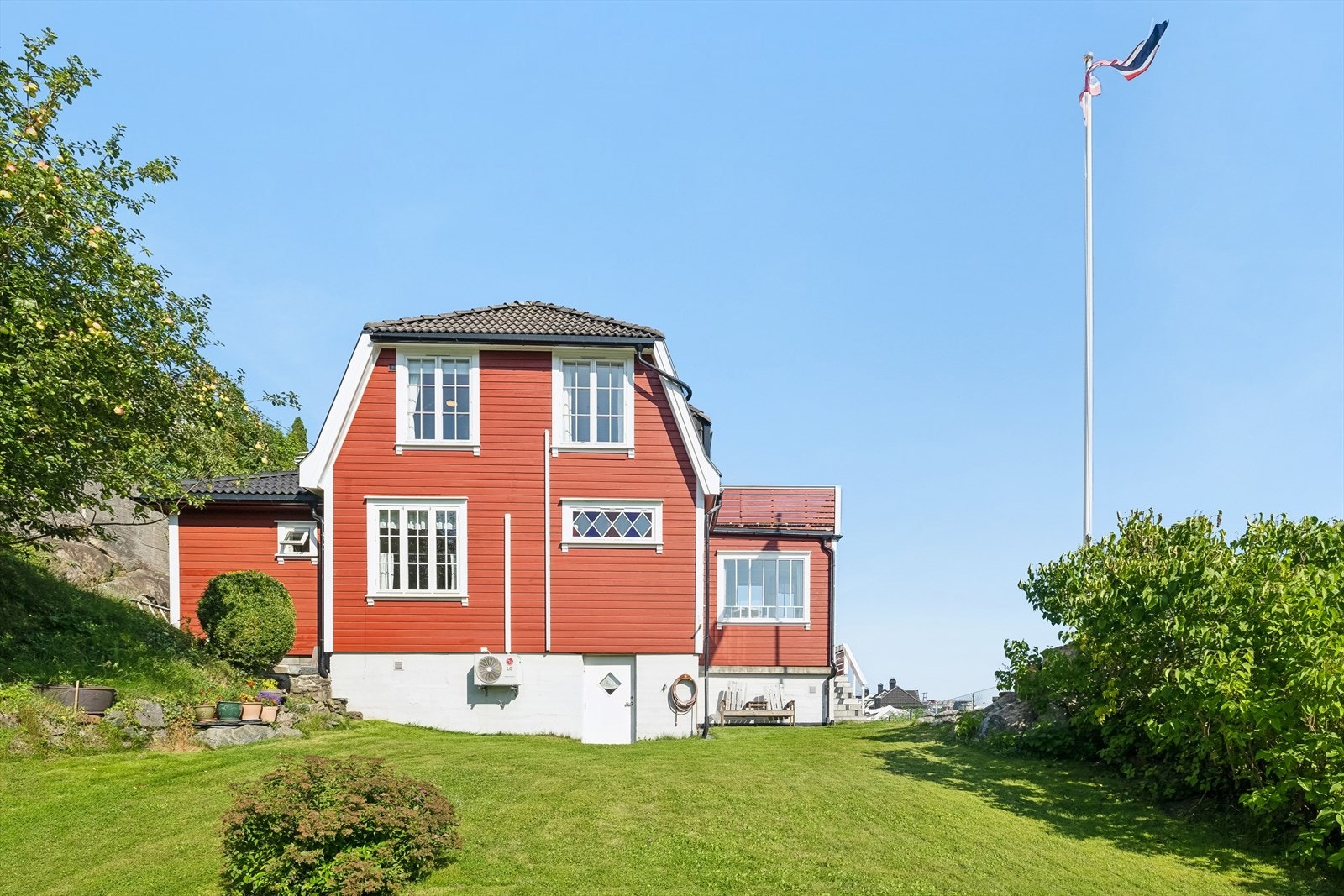 Det er en frodig hage med flere fruktrær og syrin busk. Galleribilde