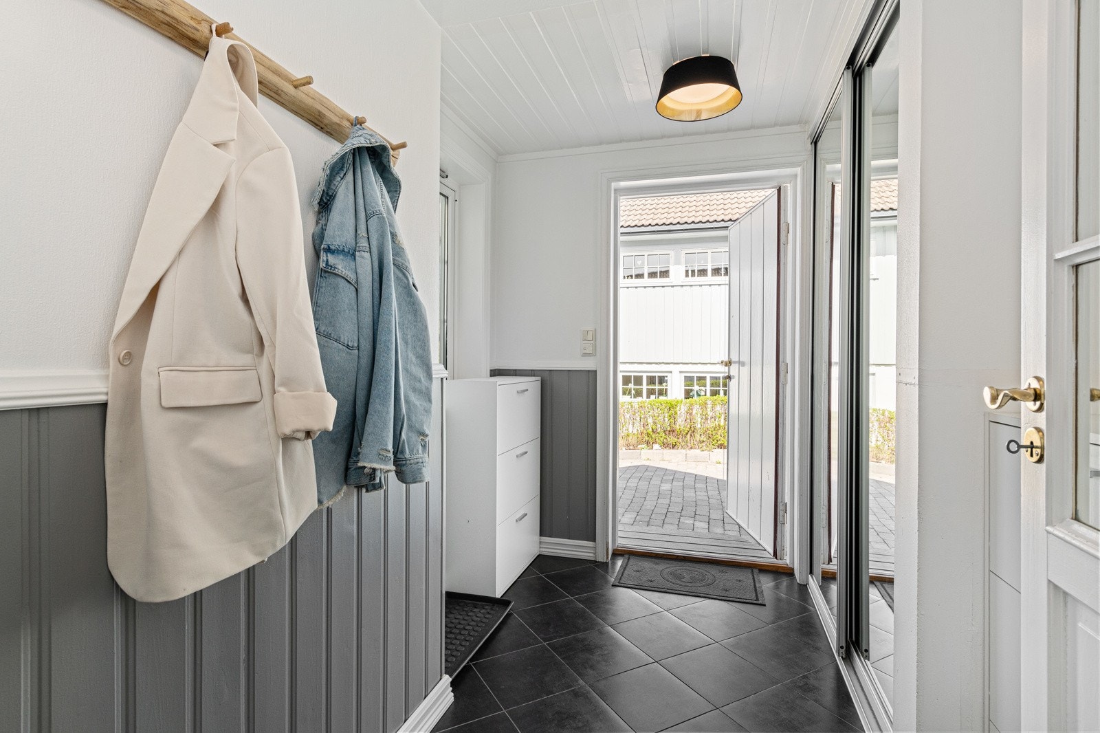 Vindfang i lyse, moderne farger. Her er det god plass til å henge fra seg yttertøy og sette fra seg sko. Det er en innebygd skyvedørsgarderobe. Galleribilde